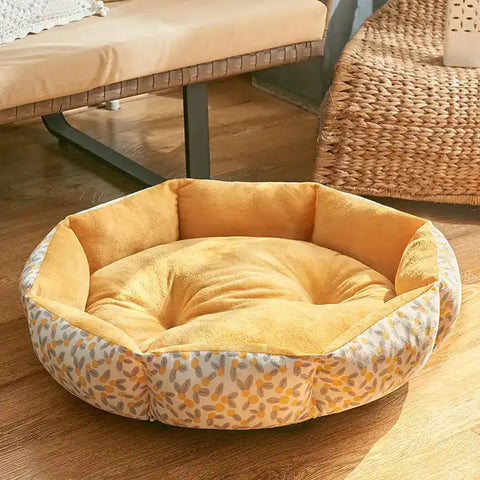 Round pet bed with yellow interior and patterned exterior on wood floor.