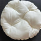 Round white cushion on a black background.