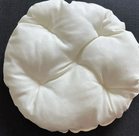 Round white cushion on a black background.
