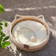 Round woven pet bed with white cushion on concrete surface.