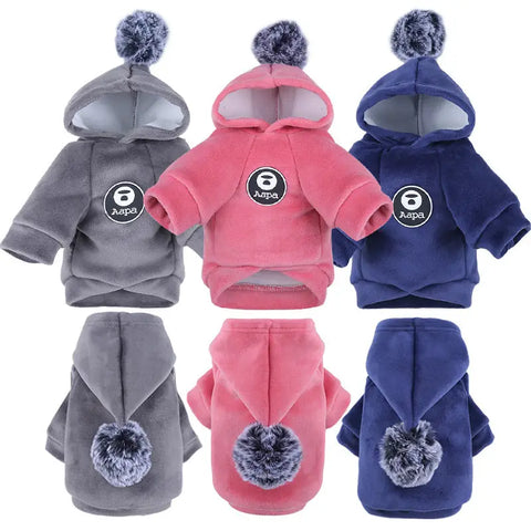 Set of three pet hoodies in gray, pink, and blue with pom-pom details.