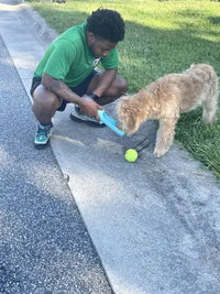 Customer review photo of a man giving water to a Goldendoodle from a lake blue Soicta water dispenser during a walk