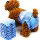 Stack of blue pet diapers next to a dog modeling a denim-style diaper.