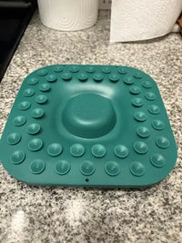 Customer review photo showcasing the bottom suction cup matrix of a teal Woof LickMat on a granite countertop.