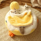 Two cats in yellow and white duck-shaped pet bed on wooden floor.