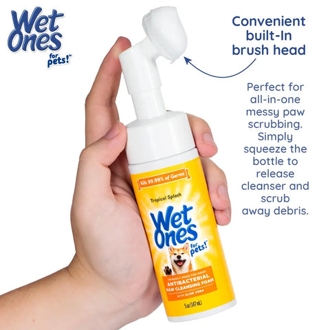 Person holding a Wet Ones for Pets paw cleansing foam bottle demonstrating the convenient built-in brush head for scrubbing messy paws.