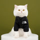 White cat wearing a black jacket with 'The Dog Face' logo.