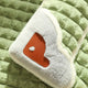 White plush toy with brown patch on green textured pet bed.