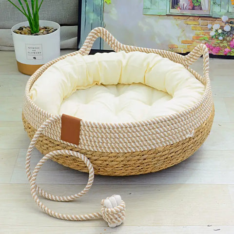Woven pet bed with a plush cushion on a wooden floor, accompanied by a small rope toy.