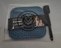 A blue Zonopy lick mat and black scraping spatula sealed inside transparent frosted retail zipper packaging with a dog logo stamp.